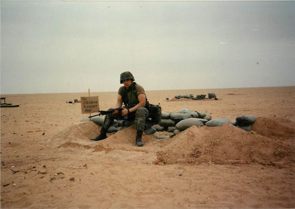 Desert fighting position with a hand-lettered sign reading The Arabian Knight Inn, Gulf War