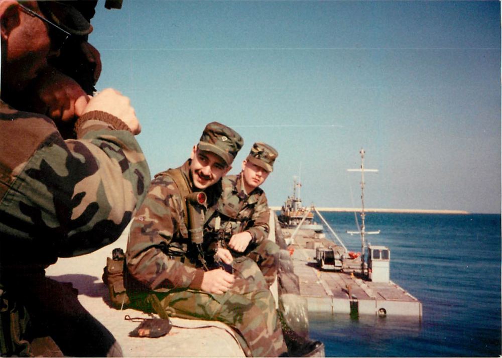 With squadmates on a pier over Gulf waters